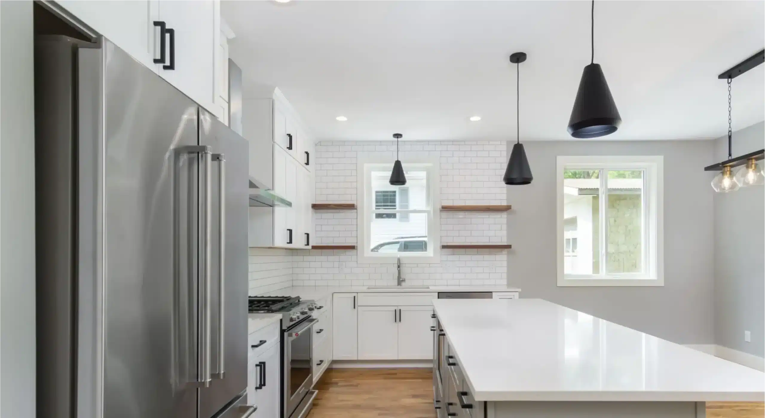 Modern white kitchen with stainless steel appliances, subway tile backsplash, and open shelving – Sure Foot Builders home in Asheville, NC