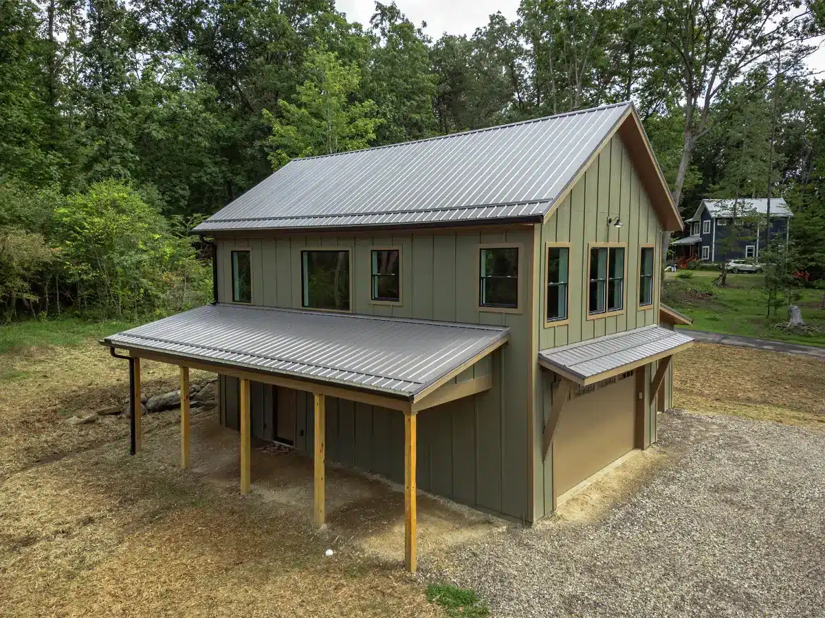 Detached two-story garage conversion ADU in Asheville, NC, featuring green board and batten siding and a large metal roof.