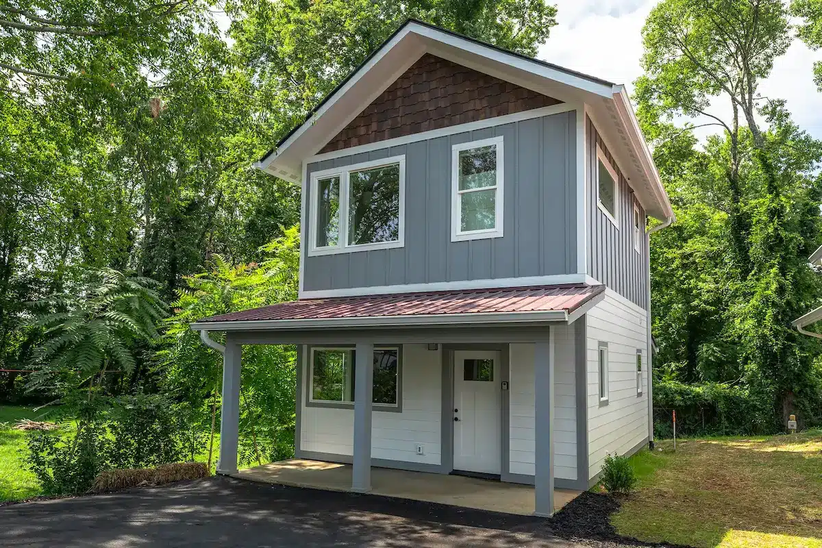 Modern two-story detached ADU in Asheville, NC, featuring grey vertical siding, a covered front porch, and custom metal roofing.