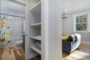 Built-in white open shelving storage system inside a home hallway or walk-in utility closet.