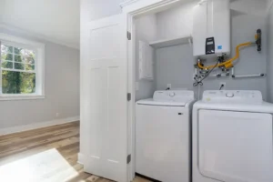 Laundry closet featuring a white top-load washer and dryer set behind clean white open doors.