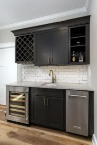 Modern home wet bar featuring dark cabinetry, an integrated wine cooler, a small undermount sink, and a white subway tile backsplash.