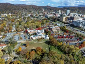 Aerial drone photograph capturing a scenic town landscape surrounded by colorful autumn trees.