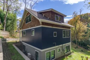 High-angle corner view of a multi-story custom house showcasing modern blue siding and window placement.