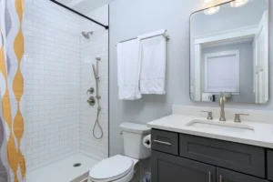 Modern bathroom interior featuring a dark grey vanity, white toilet, and a clean walk-in shower.