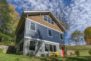 Low-angle architectural view of a craftsman home showcasing blue siding and natural cedar shake accents.