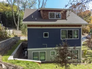 Exterior angle of a multi-story home with blue horizontal siding and a concrete block foundation wall.