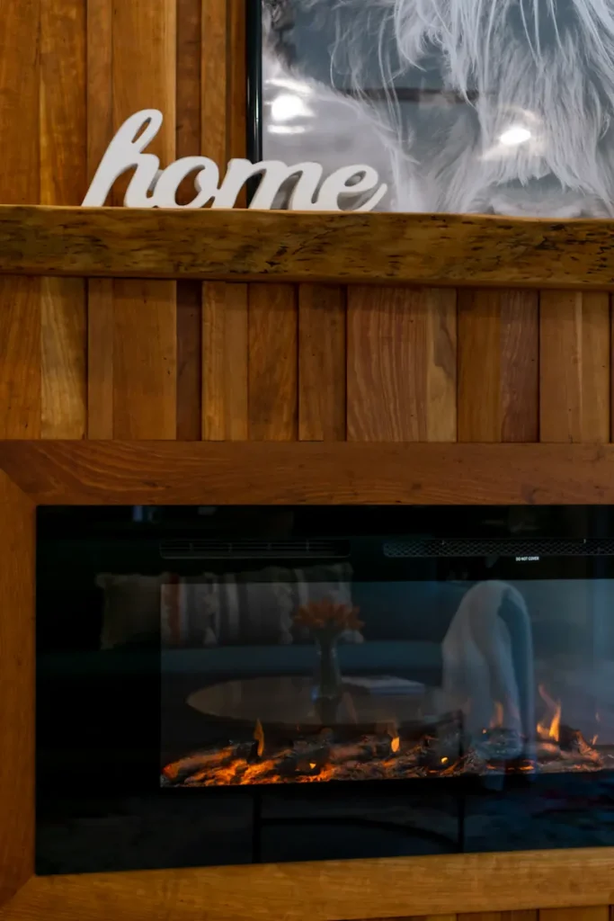 Closer up of a fireplace with a custom wooden mantel above it.