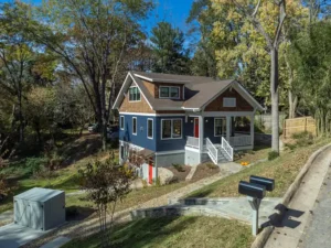 Front perspective of a newly constructed blue craftsman-style home with white trim and a covered front porch.