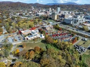 Elevated aerial drone view overlooking a scenic mountain town surrounded by vibrant autumn foliage.