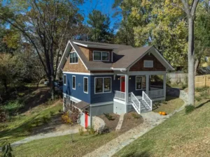 Beautiful custom craftsman home exterior featuring dark blue siding, cedar shake accents, and a stone-lined walkway.
