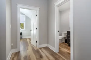 Interior hallway showcasing rich hardwood flooring, white baseboards, and open doorways leading to adjacent rooms.