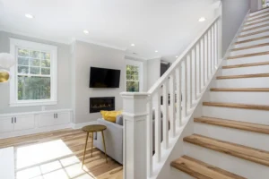 Open-concept living area highlighting a white painted staircase with wood treads and polished hardwood floors.