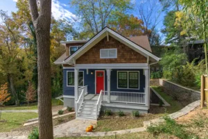 Front exterior elevation of a craftsman custom home with blue siding, cedar shake accents, white trim, and a vibrant red front door.