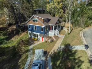 Aerial drone view of a multi-story craftsman home featuring blue siding and natural wood shingle accents.